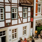 Fachwerkhaus in Brakel mit Touristen-Information; Menschen sitzen vor dem Gebäude in der Fußgängerzone.