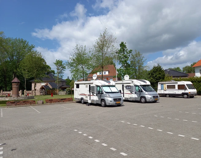 Wohnmobilstellplatz am Viehmarktplatz Der Wohnmobilstellplatz am Viehmarktplatz zeigt drei Wohnmobile, die auf einem gut gepflasterten Parkplatz vor beigefarbenen Steinhäusern mit roten Dächern und üppigen grünen Bäumen stehen. Der blaue Himmel ist leicht bewölkt.
