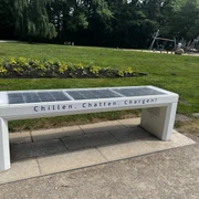 SmartBench SmartBench mit integriertem Solarpanel in einem grünen Park, ausgestattet mit dabei USB-Ladeanschlüssen.