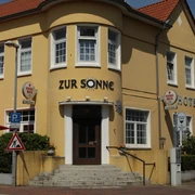 Gelbes Gebäude des Hotel zur Sonne mit roten Dächern und seitlichen Treppen.
