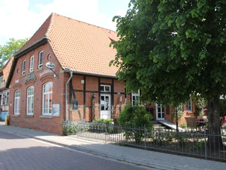 Restaurant Ephesus am Weserwehr, ein Backsteinhaus mit roten Dachziegeln, umgeben von Grün.