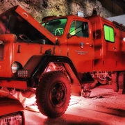 Feuerwehrmuseum Heiligenhaus Ein leuchtend rotes historisches Feuerwehrfahrzeug parkt unter einem stimmungsvoll ausgeleuchteten Vordach.