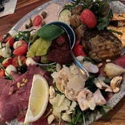 Antipasti Eine bunte Platte mit verschiedenen Antipasti, darunter Oliven, Salami, Tomaten und Käse.