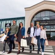 Halle Leipzig The Style Outlets - Shopping in Leipzig Eine Familie verlässt lachend und mit Einkaufstüten in der Hand das Halle Leipzig The Style Outlets Center, Shopping, Einkaufen, Freizeit, Familie, Ausflug