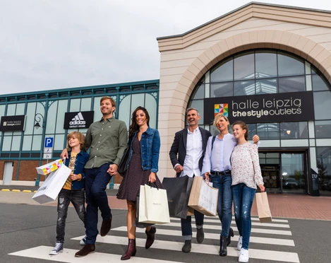 Halle Leipzig The Style Outlets - Shopping in Leipzig Eine Familie verlässt lachend und mit Einkaufstüten in der Hand das Halle Leipzig The Style Outlets Center, Shopping, Einkaufen, Freizeit, Familie, Ausflug