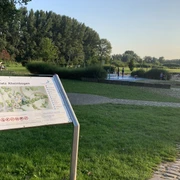 Rheinbogen mit Wasserspielplatz in Monheim am Rhein Freizeitfläche mit Spielplatz in grüner Umgebung am Rhein, Spielgeräte und Besucher im Hintergrund.