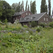 Naturschutzzentrum Bruchhausen in Erkrath Ein historisches Backsteingebäude umgeben von einer üppigen, vielfältigen Gartenlandschaft im Naturschutzgebiet.