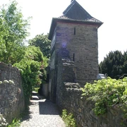 Trinsenturm in Ratingen Ein historischer Steinturm flankiert von einer verwinkelten, mit Kopfsteinpflaster bedeckten Gasse.