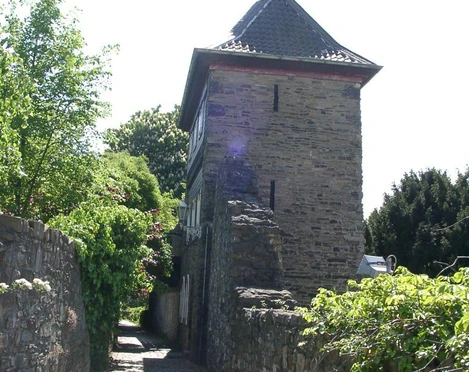 Trinsenturm in Ratingen Ein historischer Steinturm flankiert von einer verwinkelten, mit Kopfsteinpflaster bedeckten Gasse.