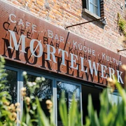 Moertelwerk - Gastronomie in Leipzig Blick auf die Backsteinfassade mit Schriftzug Moertelwerk, umrandet von Pflanzen, gastronomie, freisitz