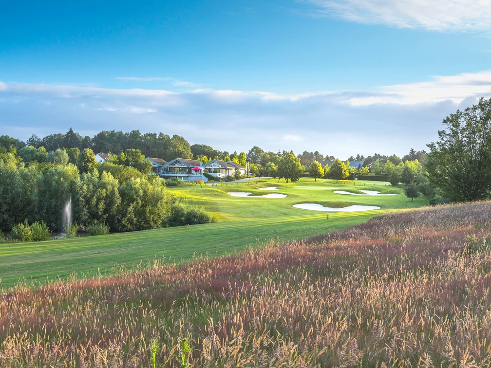 Golfclub Hösel in Heiligenhaus Golfplatz mit gepflegtem Grün und Bunkern, umgeben von Bäumen und einem Clubhaus im Hintergrund.
