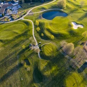 Golfclub Mettmann e.V. Luftaufnahme eines Golfplatzes mit grünen Fairways, Seen, Sandbunkern und angrenzendem Klubhaus.