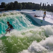 Surfing bei Wasserski Langenfeld Ein Surfer balanciert mit ausgebreiteten Armen auf einer künstlichen stehenden Welle im Park.