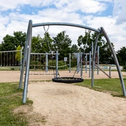 Spielplatz Am Sandbach in Ratingen Ein moderner Spielplatz mit Klettergerüsten und Schaukeln, umgeben von grünen Bäumen und Wiesen.