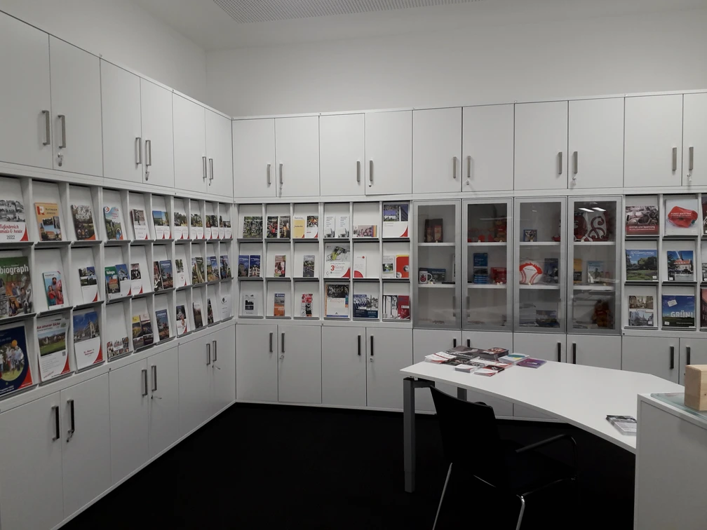 Tourist-Information Ratingen Reiseführer und Broschüren in einem Informationszentrum mit weißen Schränken und einem Tisch.
