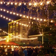 Blotschenmarkt-in-Mettmann-Titelbild.jpg Nächtlicher Weihnachtsmarkt in Mettmann mit festlicher Beleuchtung und einem dekorierten Tannenbaum.