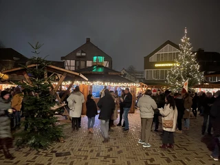 Weihnachtsmarkt2021_Am Offers_Stadtelbert_Hantich_IMG_5611.jpg Eine festlich beleuchtete Weihnachtsmarkt-Szene mit besuchenden Personen und einem großen Weihnachtsbaum.