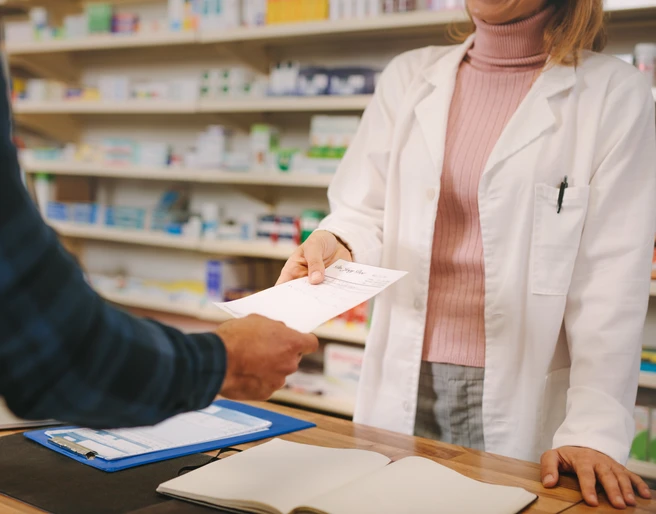 Customer handing over a prescription to the chemist Customer handing over a prescription to the chemist