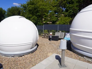 Volkssternwarte Langwedel Kuppeln und Solarpanels der Volkssternwarte Langwedel, umgeben von Bäumen bei Sonnenschein.