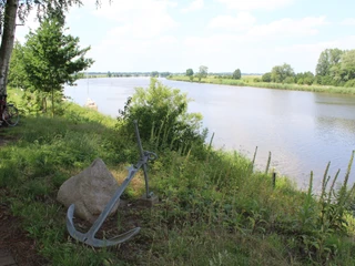Weser bei Heimsen Ein Metallanker liegt am Ufer der Weser bei Heimsen, umgeben von grüner Vegetation und Bäumen.