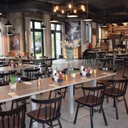 Restaurant Zur Gießerei im Best Western plus Parkhotel Velbert Restaurant mit modernen Holztischen und dunklen Stühlen, umgeben von großen Fenstern und stilvoller Beleuchtung.