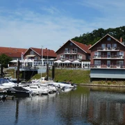 Ein Hotel-Restaurant mit roten Backsteinwänden am Ufer, umgeben von Booten am ruhigen Wasser.