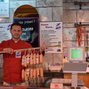 Naturfleischerei Janutta in Velbert Fleischer in roter Jacke präsentiert stolz eine Vielzahl an frischen Würsten in traditioneller Metzgerei.