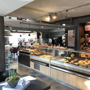 Droste Cafe, Konditorei u. Catering in Ratingen Ein helles Cafe mit Theken voller Gebäck und Kuchen, umgeben von modernem Interieur und Sitzplätzen.