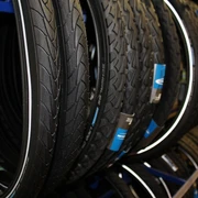 Fahrradzubehör  Verschiedene Fahrradreifen hängen dicht beieinander im Regal eines Fachgeschäfts für Fahrradzubehör.