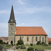 Elisabethkirche Die Elisabethkirche steht mit ihrem spitzen Turm auf einem gepflegten Friedhof unter blauem Himmel.