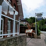 Traditionelles Gasthaus in Backsteinbauweise mit überdachtem Eingang und urigen Holzelementen.