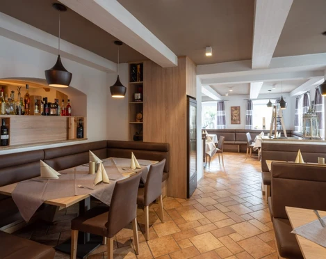 Da Giovanni Farchant - Innenbereich 2 Innenbereich mit braunen Ledereckbänken und Stühlen und einem Regal mit Wein- und Spirituosenflaschen