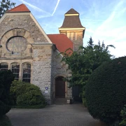 Neanderkirche in Erkrath Neanderkirche in Erkrath: Historische Backsteinkirche mit Turm, umgeben von grünen Pflanzen und Bäumen.