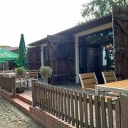 Cafe Weserscheune in Buchholz Hölzerne Terrasse des Cafés mit rustikalen Zäunen, Sonnenschirmen und Holzbänken im Freien.