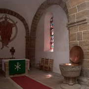 Im Inneren der Kirche Buchholz sind der Altar mit hohem Kreuz und ein farbenreiches Fenster zu sehen.
