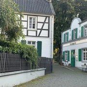 Restaurant bloomgold in Monheim am Rhein Restaurant bloomgold in Monheim am Rhein mit weißer Fassade, grünen Fensterläden und Kopfsteinpflaster.