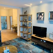 Besotel Mettmann Modern eingerichtetes Wohnzimmer mit hellen Wänden, einem großen Fernseher und stilvollen Dekorationen.