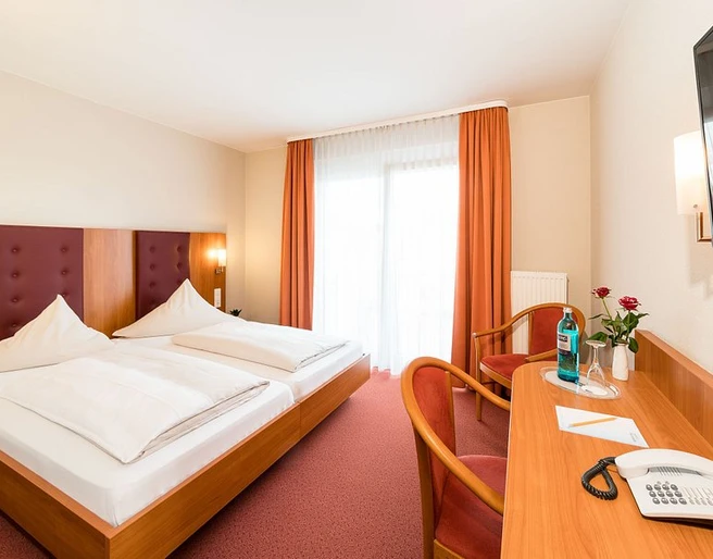 Hotelzimmer im Hotel-Restaurant Zum Vater Rhein in Monheim am Rhein Hotelzimmer mit zwei Einzelbetten, Schreibtisch, Flachbildfernseher, helle Vorhänge und rote Dekore.