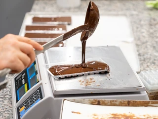 Schokoladentafel der Chocolaterie Praetsch - Regionale Produkte Auf einer Waage wird eine Schokoladentafel der Chocolaterie Praetsch in Wermsdorf händsich gegossen und abgewogen, regionale ProdukteChocolate is poured by hand into a mould for chocolate bars on the scales at Chocolaterie Praetsch, regional products