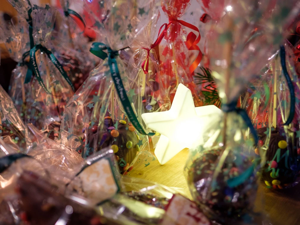 Adventsplaetzchen.jpg Festliche Plätzchen in bunten Tütchen, umrahmt von leuchtendem Stern, schaffen weihnachtliche Atmosphäre.