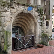 WunstorfInfo01.jpg Historischer Eingang zur Stadtbücherei mit Rundbogen und alten Steinverzierungen in einer urbanen Umgebung.