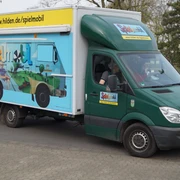 Spielmobil Hilden Ein grüner Lieferwagen des Spielmobils Hilden mit buntem Grafitti parkt auf einer Straße.