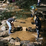 Bau eines Staudammes auf dem Abenteuerspielplatz Hilden Kinder spielen am Bachlauf und errichten einen kleinen Staudamm mit Steinen auf einem Abenteuerspielplatz.