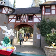 Freizeitpark_Sommerrodelbahn_SaisoneröffnungOstern.JPG Ein Osterhase in einem Korb voller bunter Eier vor einem märchenhaften Gebäude mit zwei Türmen.