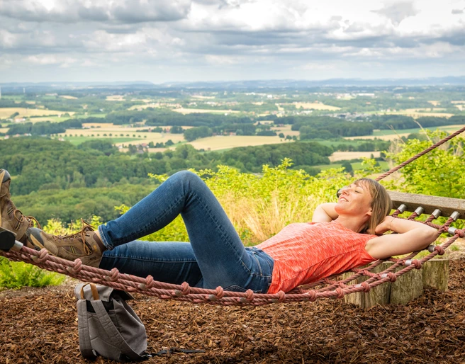 Werther-Hermannshöhen-Teutoburger-Wald-Tourismus-D-Ketz-087.jpg Frau liegt entspannt in der Hängematte mit Blick auf die hügelige Landschaft des Teutoburger Waldes.