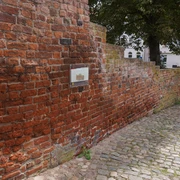 Stadtmauer Sandberg Verden Rote Backsteinmauer aus dem Mittelalter in Verden, durchzogen von einem gepflasterten Weg.