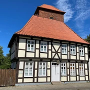 Alter Wehrturm Verden mit Scharfrichterhaus Fachwerkgebäude mit rotem Ziegeldach und gemauertem Turm in Verden unter klarem, blauem Himmel.