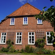 Dauelsen Alte Schule Backsteinfassade der Alten Schule in Dauelsen mit gepflegtem Garten, Fenster mit weißen Sprossen.