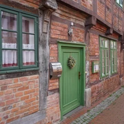 Budenhäuser Verden Fachwerkhäuser mit roten Ziegelwänden, weißen Fenstern und grünen Türen entlang einer Pflastergasse.