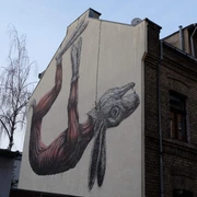 Mural Ein beeindruckendes Mural zeigt detailreich einen großen Hasen, der an einer Wand hängend abgebildet ist, dies verleiht der Gebäudefassade eine einzigartige Note.An impressive mural depicts a large rabbit hanging on a wall in great detail, giving the building façade a unique touch.